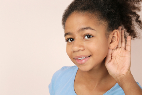 young girl holding hand against ear