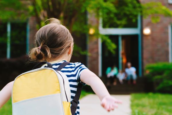 young girl with backpack running home from school