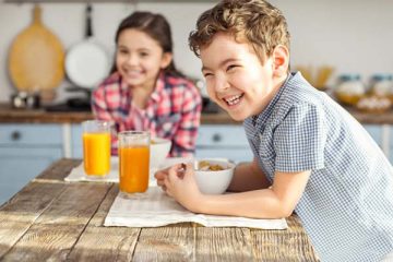 Two smiling kids eating breakfast