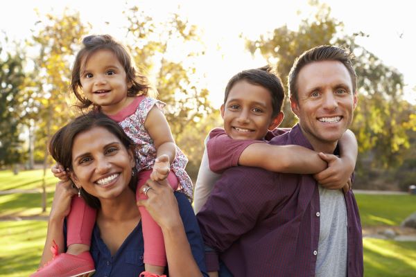 smiling parents carrying their two children in the park