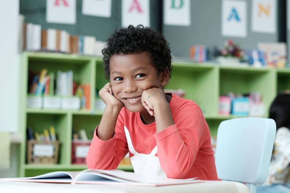 Smiling kid sitting at a desk in classroom