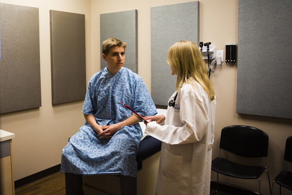 teen boy getting checkup with female doctor