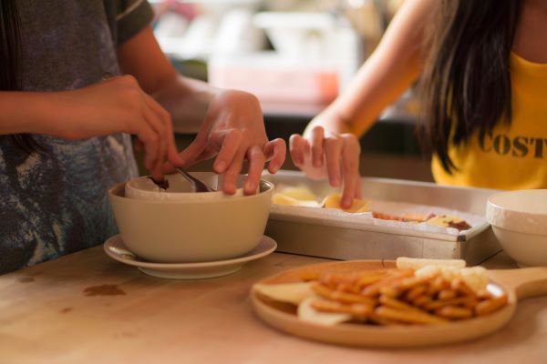 ”children's hands picking at food on table