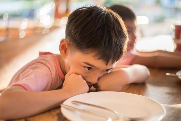 upset boy resting head at the dinner table