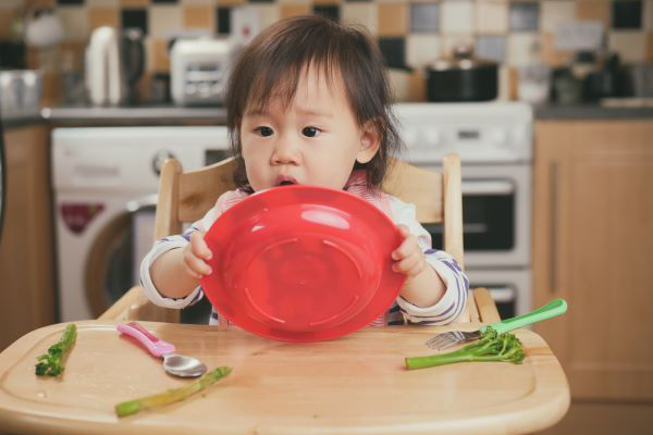 toddler on high chair playing with plate of food