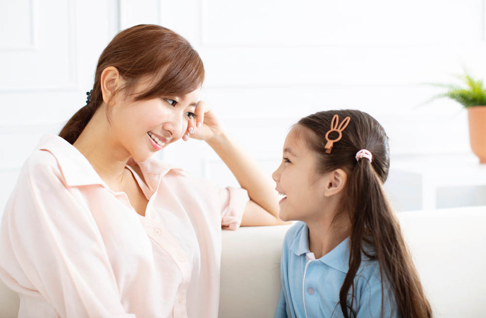 mother and young daughter talking and smiling