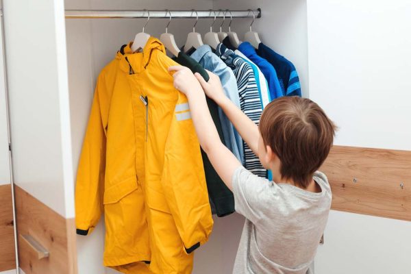 Boy arranges clothes in closet
