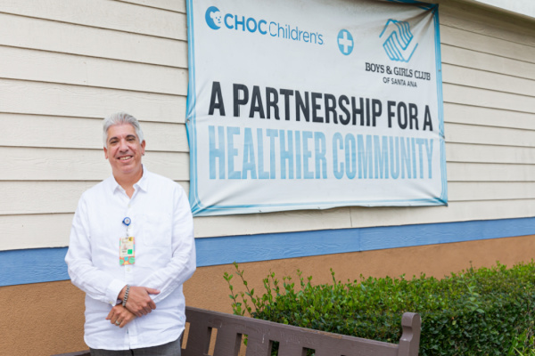 A male pediatrician stands outside the clinic