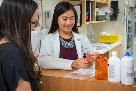 pharmacist reviews inhaler instructions with customer