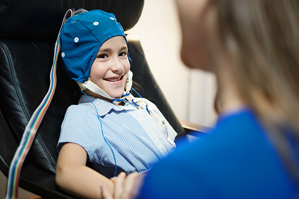 young girl smiles while receiving an EEG test