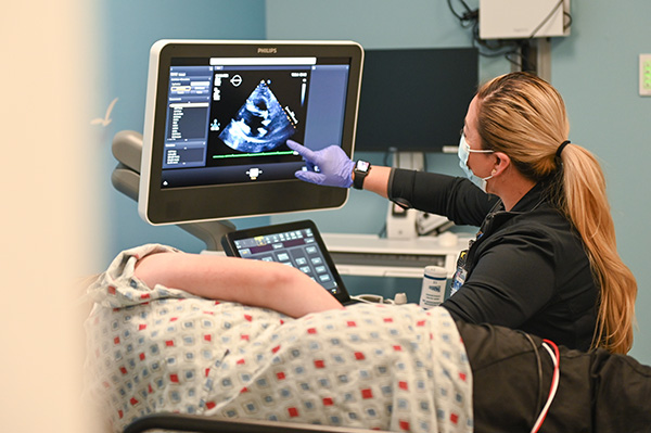 Technician performs fetal echocardiogram for a patient and points to screen