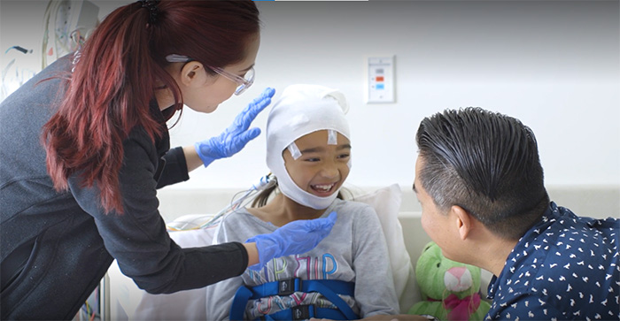 Young girl smiles at father and technician during a sleep study