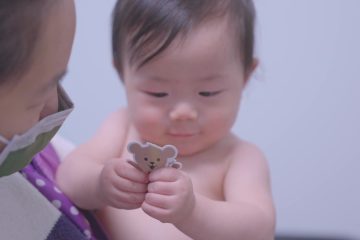 A mother and her child smiling while holding a Choco sticker at a CHOC primary care location