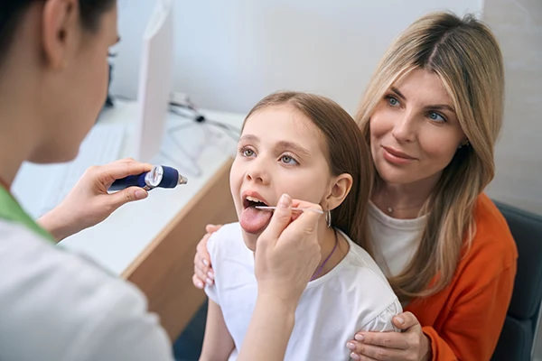 Otolaryngologist examining little girl's throat
