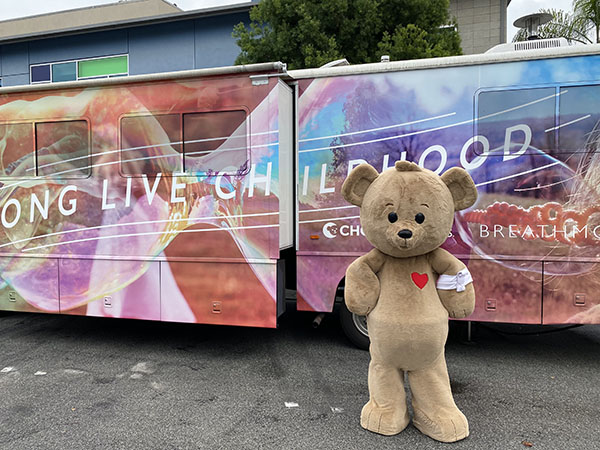 Choco bear stands in front of a Wellness on Wheels RV