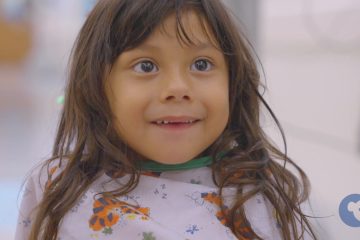 Young child smiling in a patient gown.